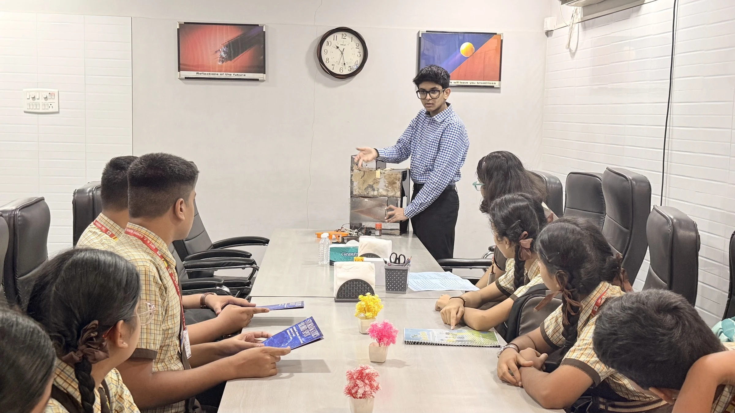 Aarav and students discussing a water-treatment setup at a school table