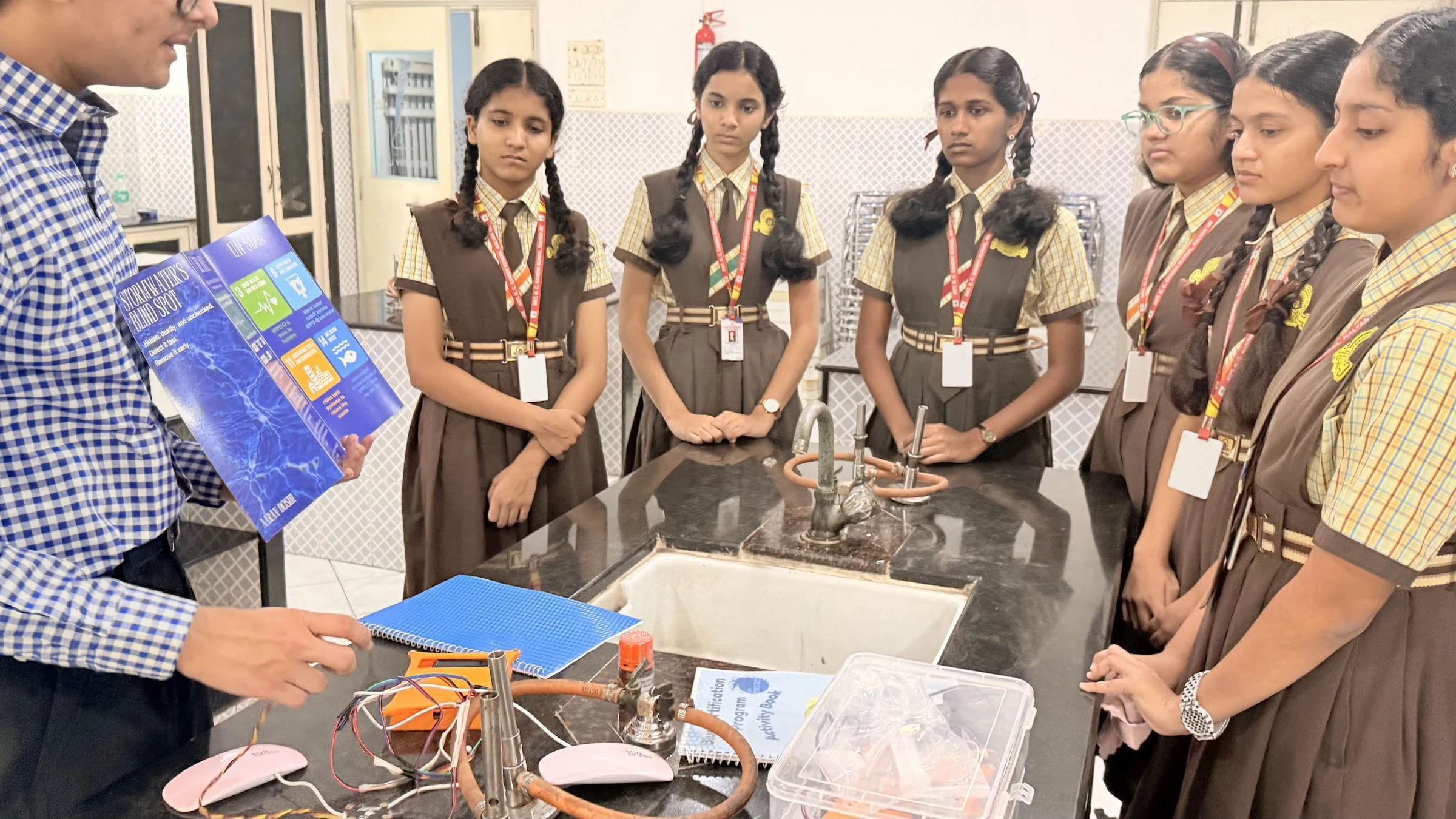 Students gathered around laboratory apparatus and the Blue Book