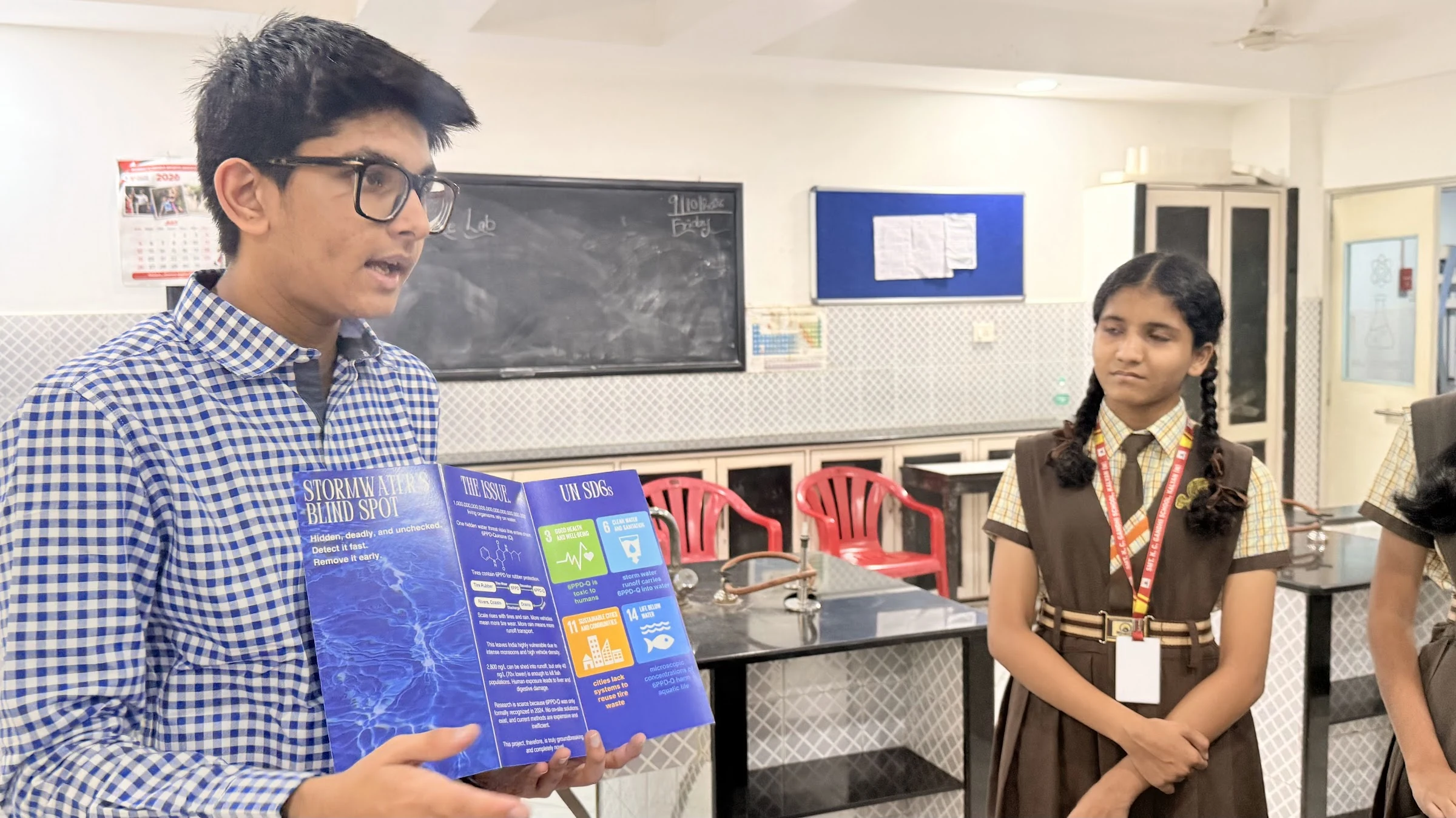 Aarav explaining the learning material to students beside the laboratory equipment