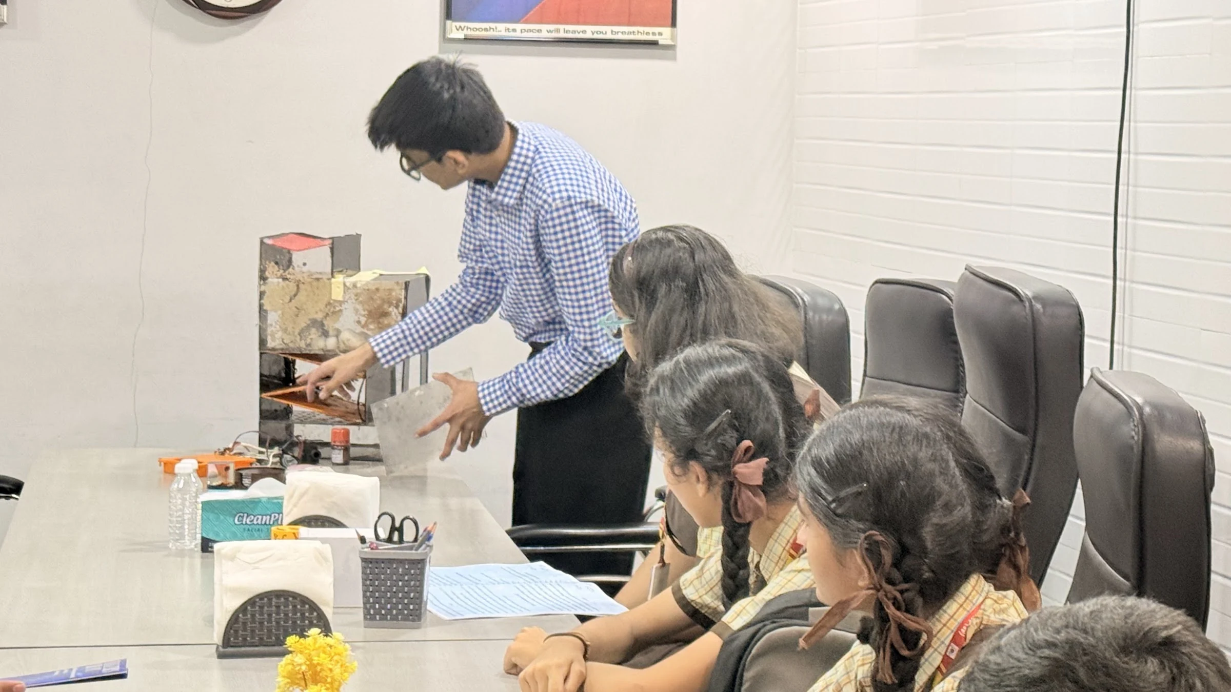 Students watching a water-treatment demonstration around a meeting table
