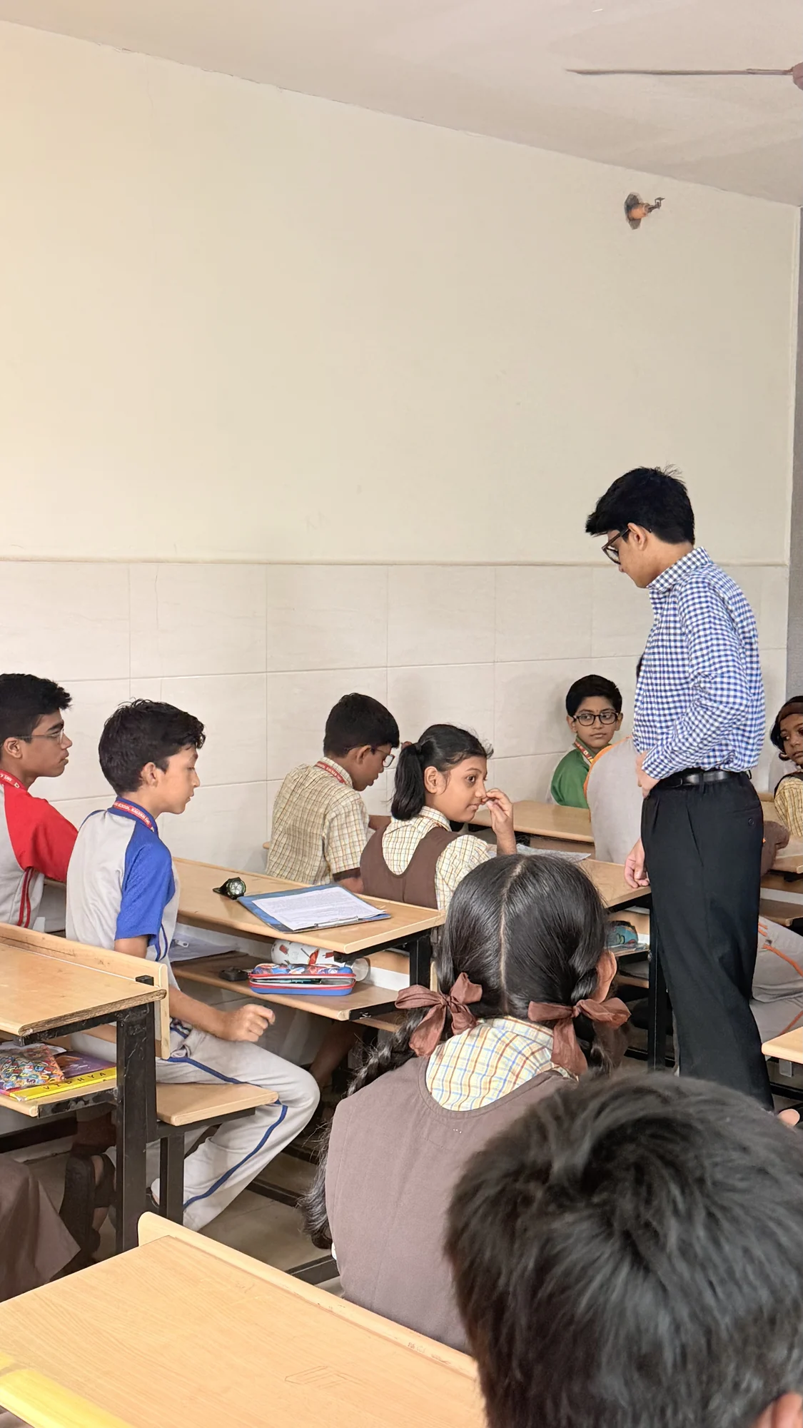 A facilitator speaking with students at their classroom desks