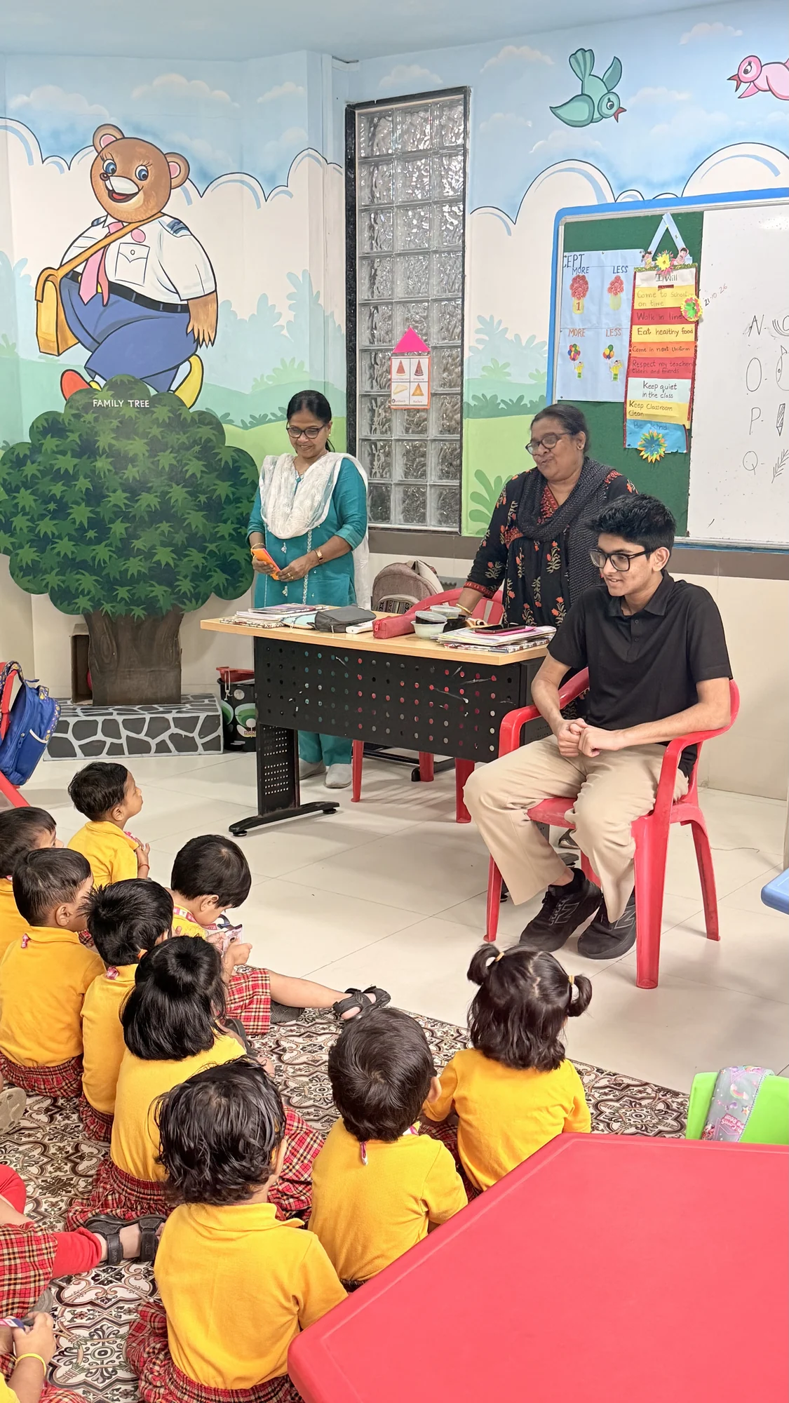 A facilitator seated with children during a classroom activity