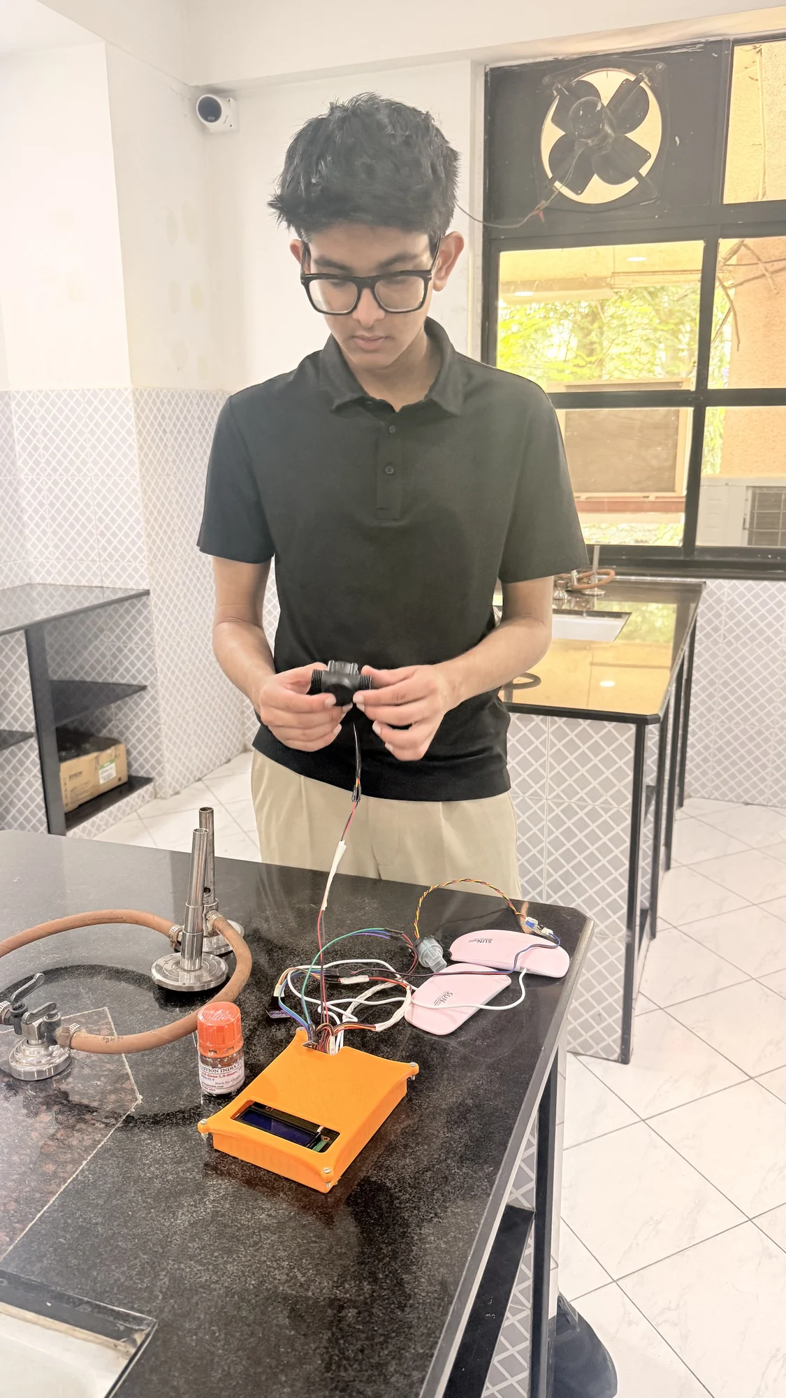 A student researcher examining electronic equipment on a laboratory bench